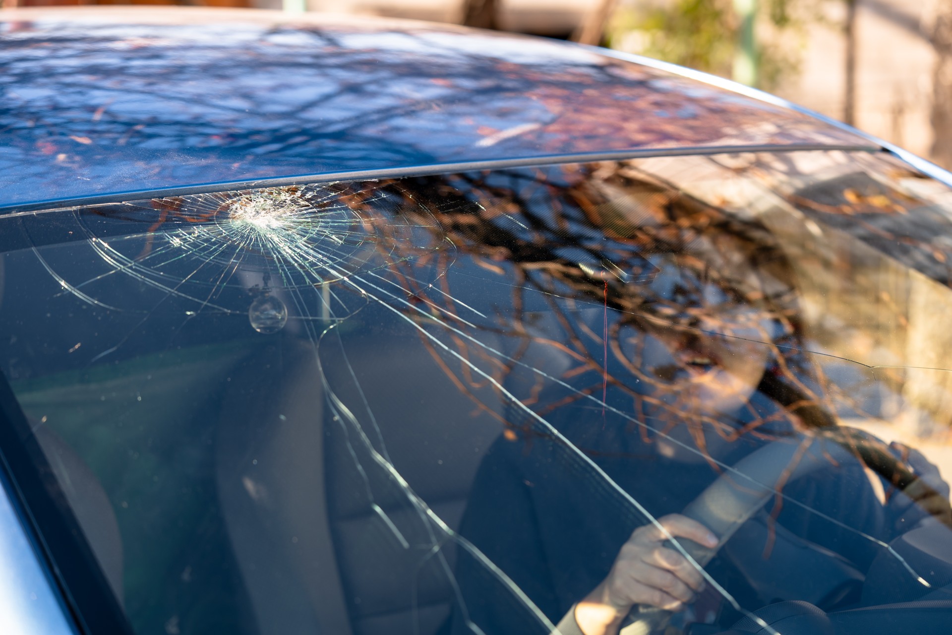 Shocked woman in car with broken windshield  and cracks. Car accident. Selective focus