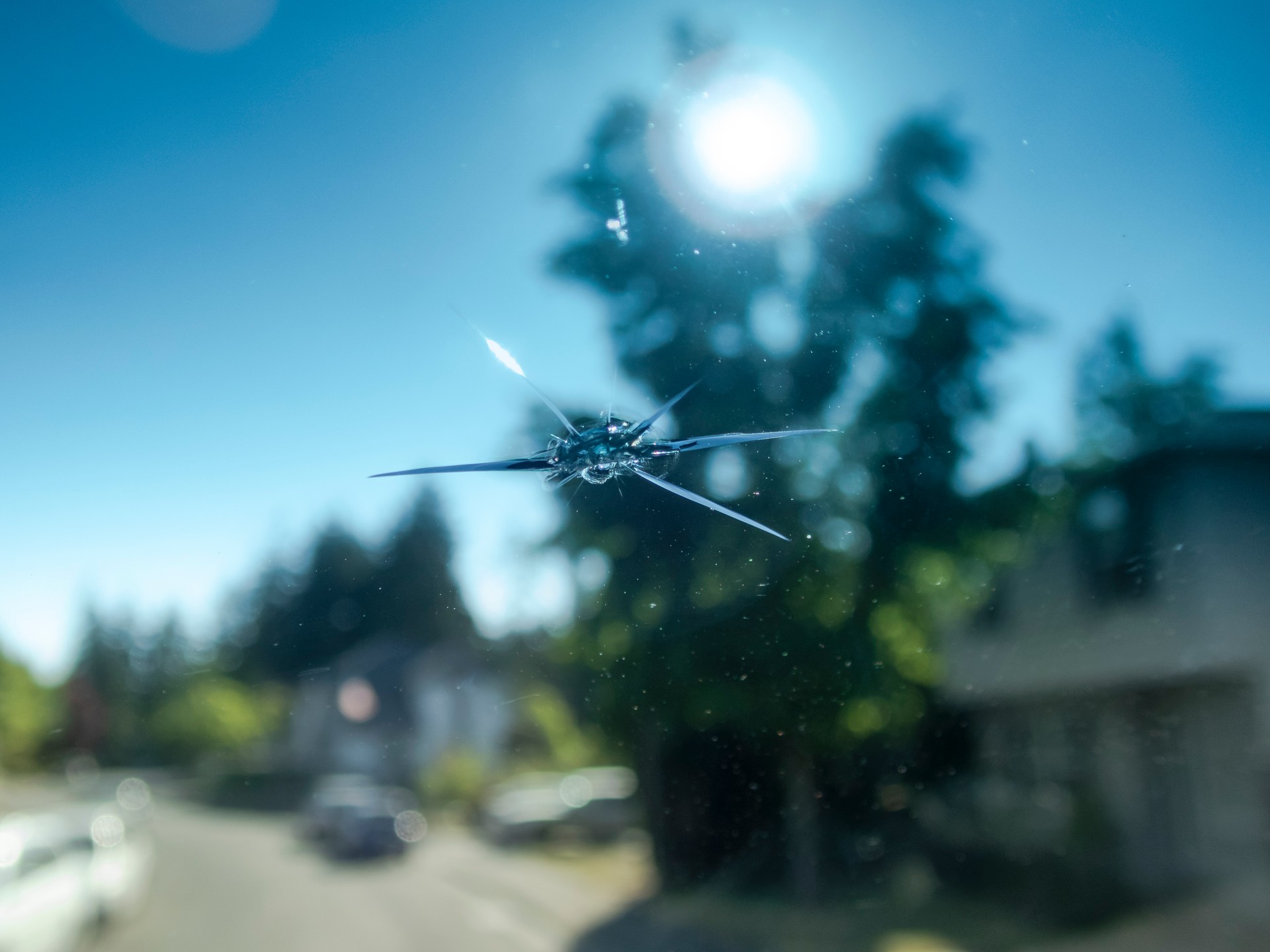 Rock Chip in Windshield of Car Close-up Street Background